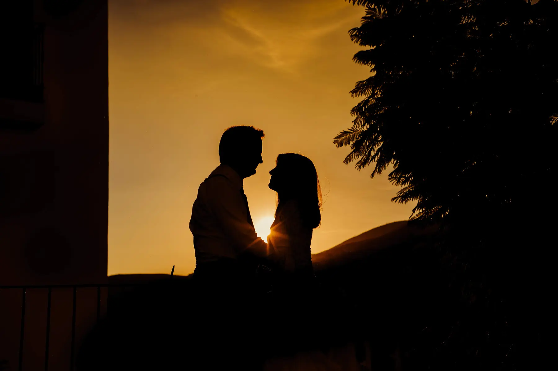 Siluetas de una pareja frente al cielo dorado del atardecer