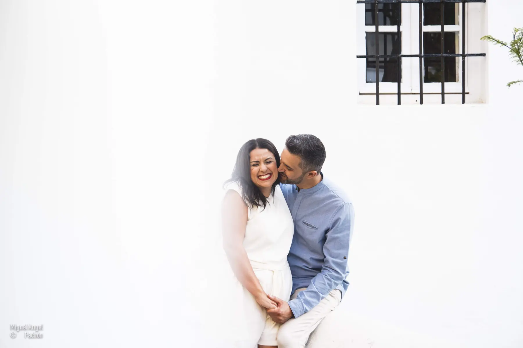 Pareja abrazada junto a una pared blanca