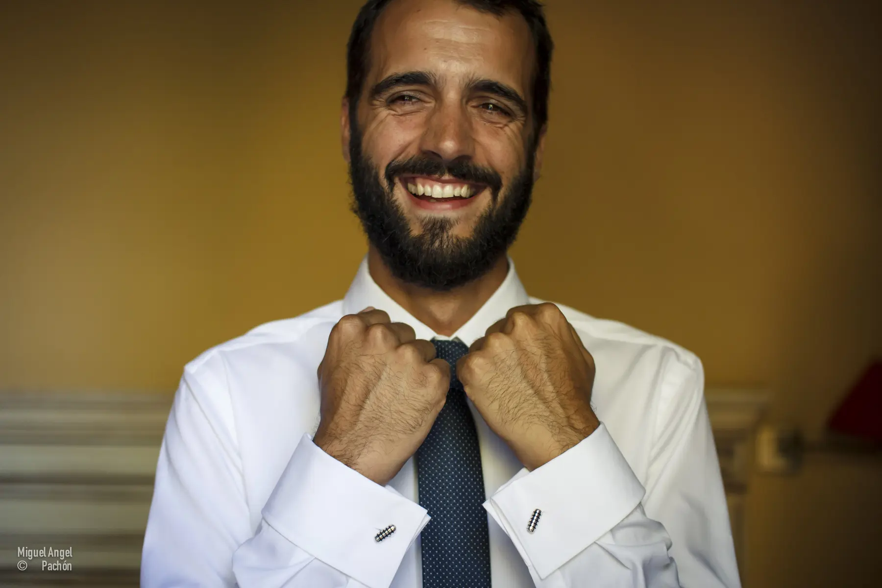 Novio sonriente ajustándose la corbata
