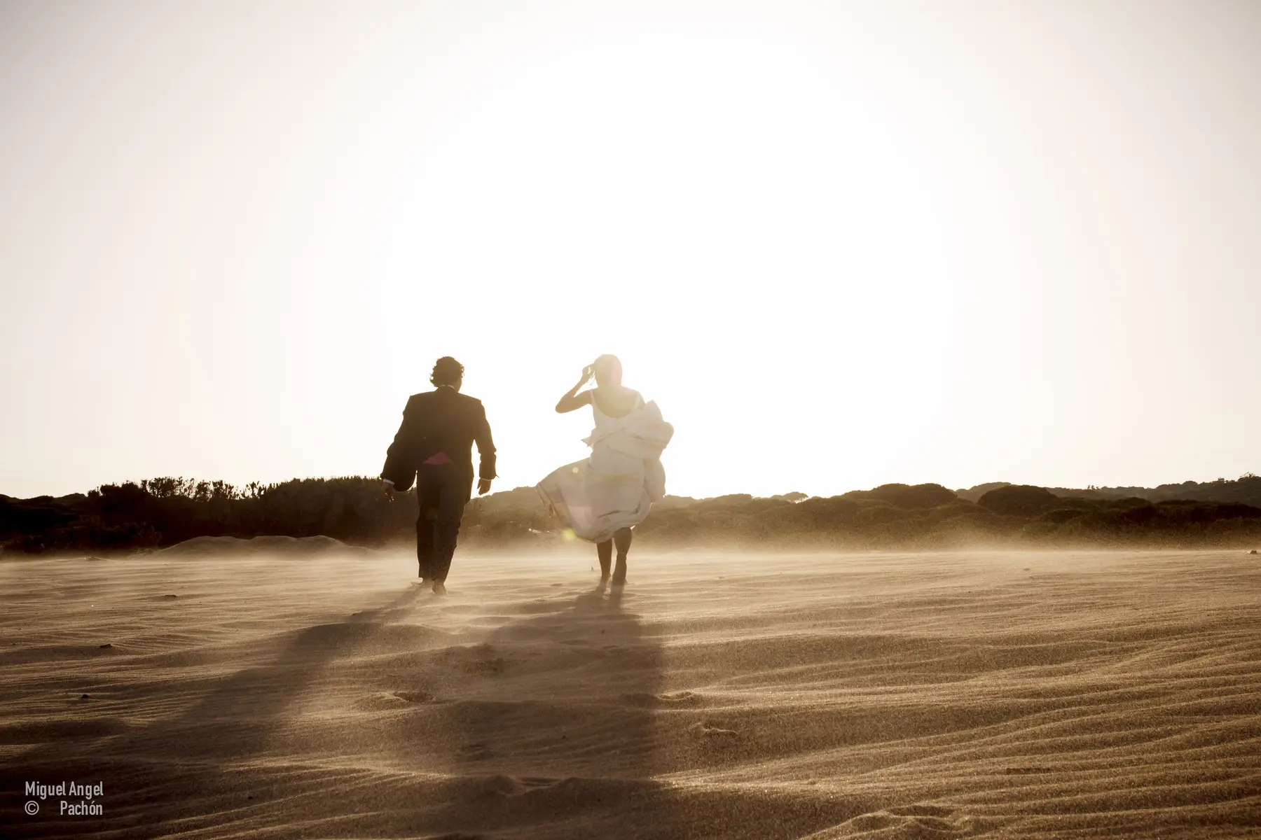 Pareja caminando entre dunas a contraluz