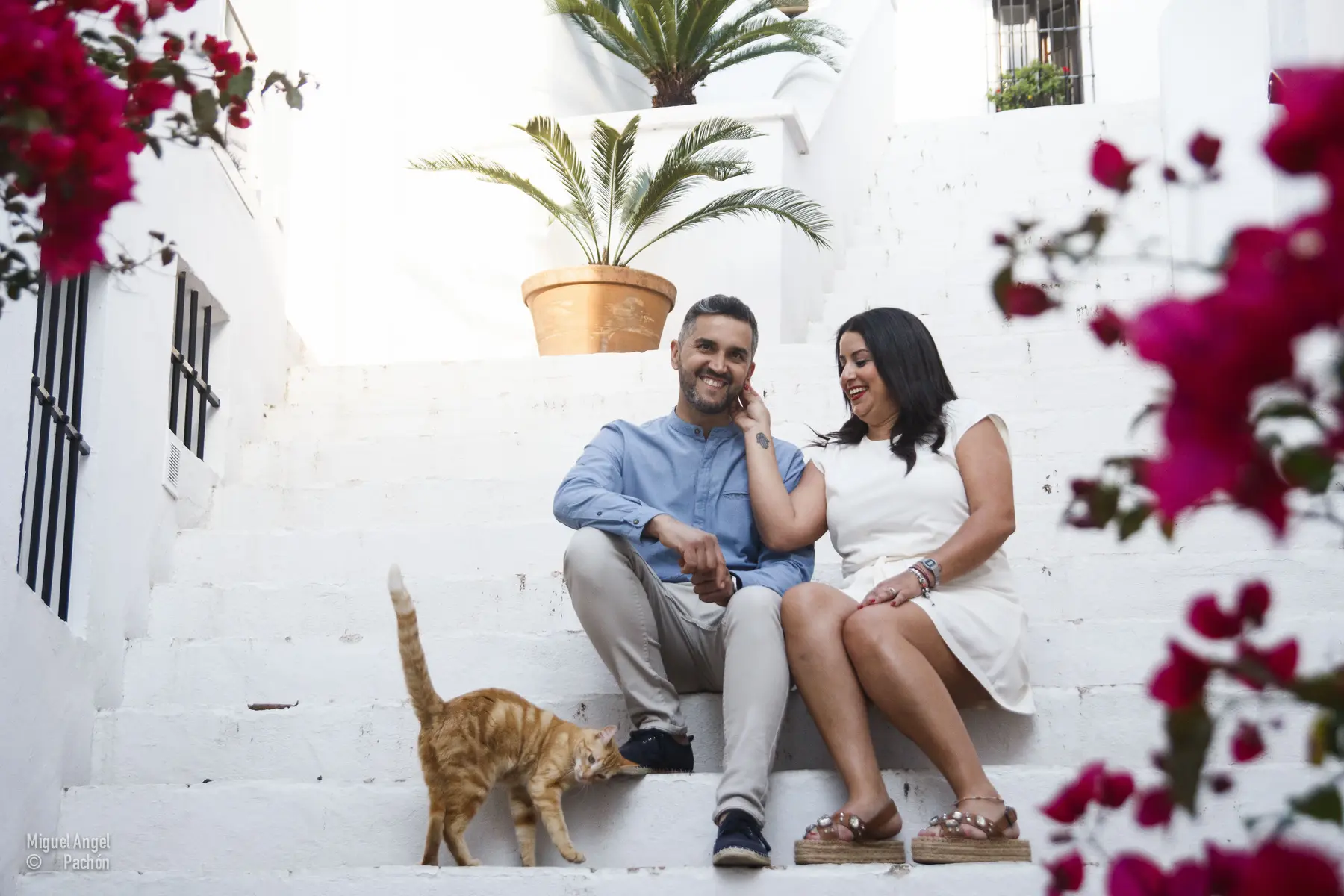 Pareja sentada entre paredes blancas y flores