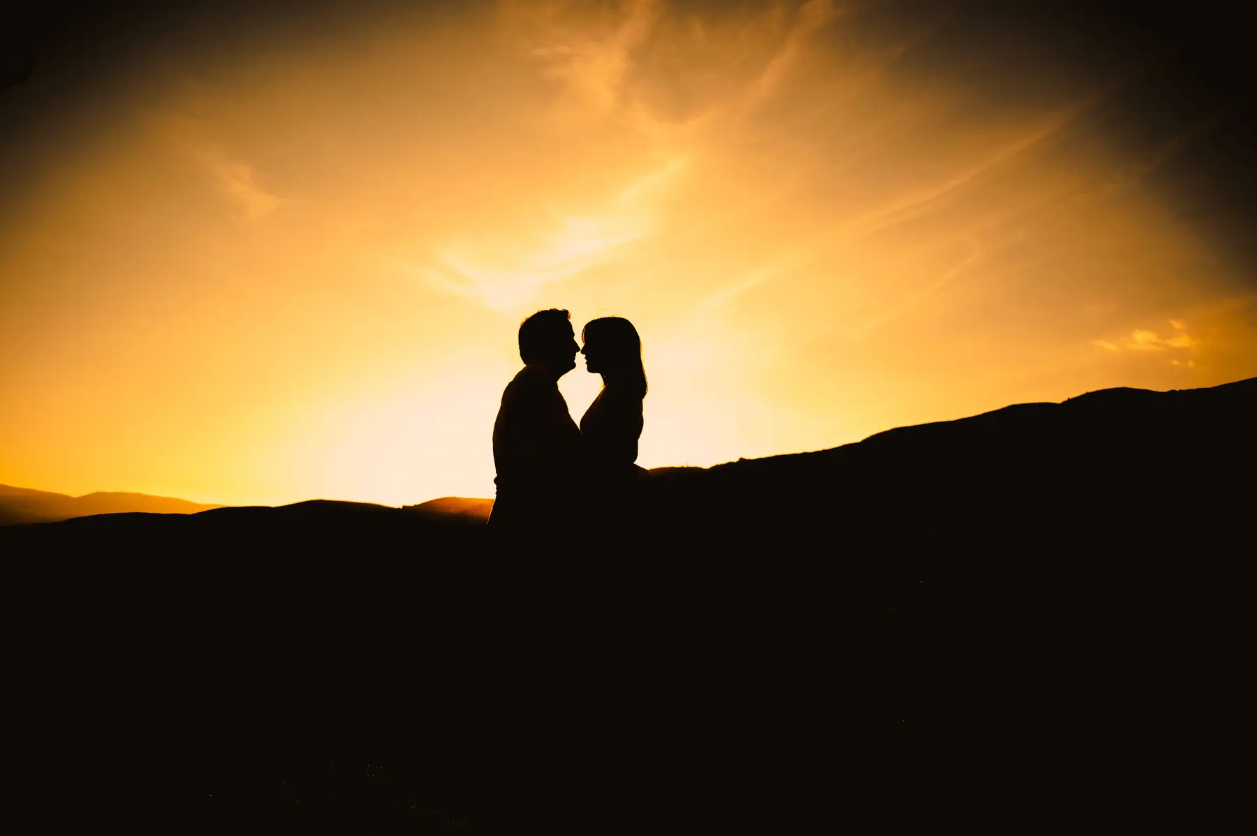Beso de una pareja en silueta frente al atardecer