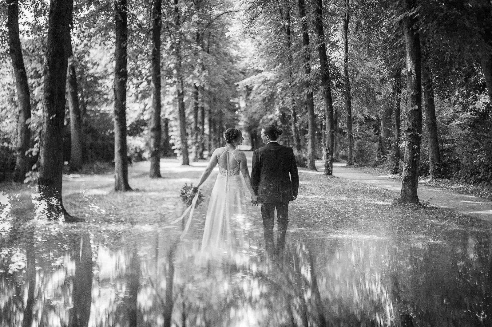 Novios caminando entre árboles en blanco y negro