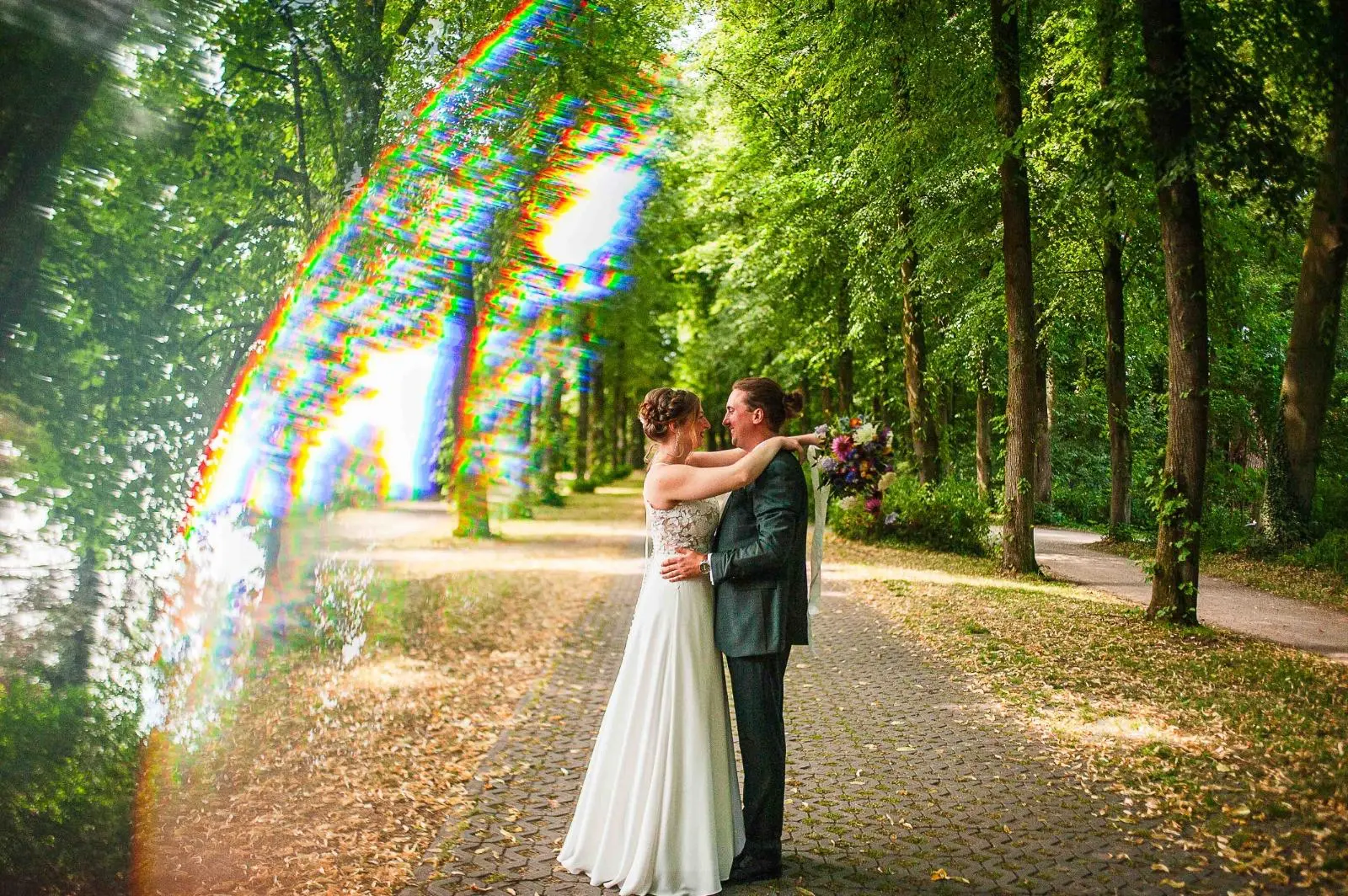 Novios abrazados en un sendero entre árboles