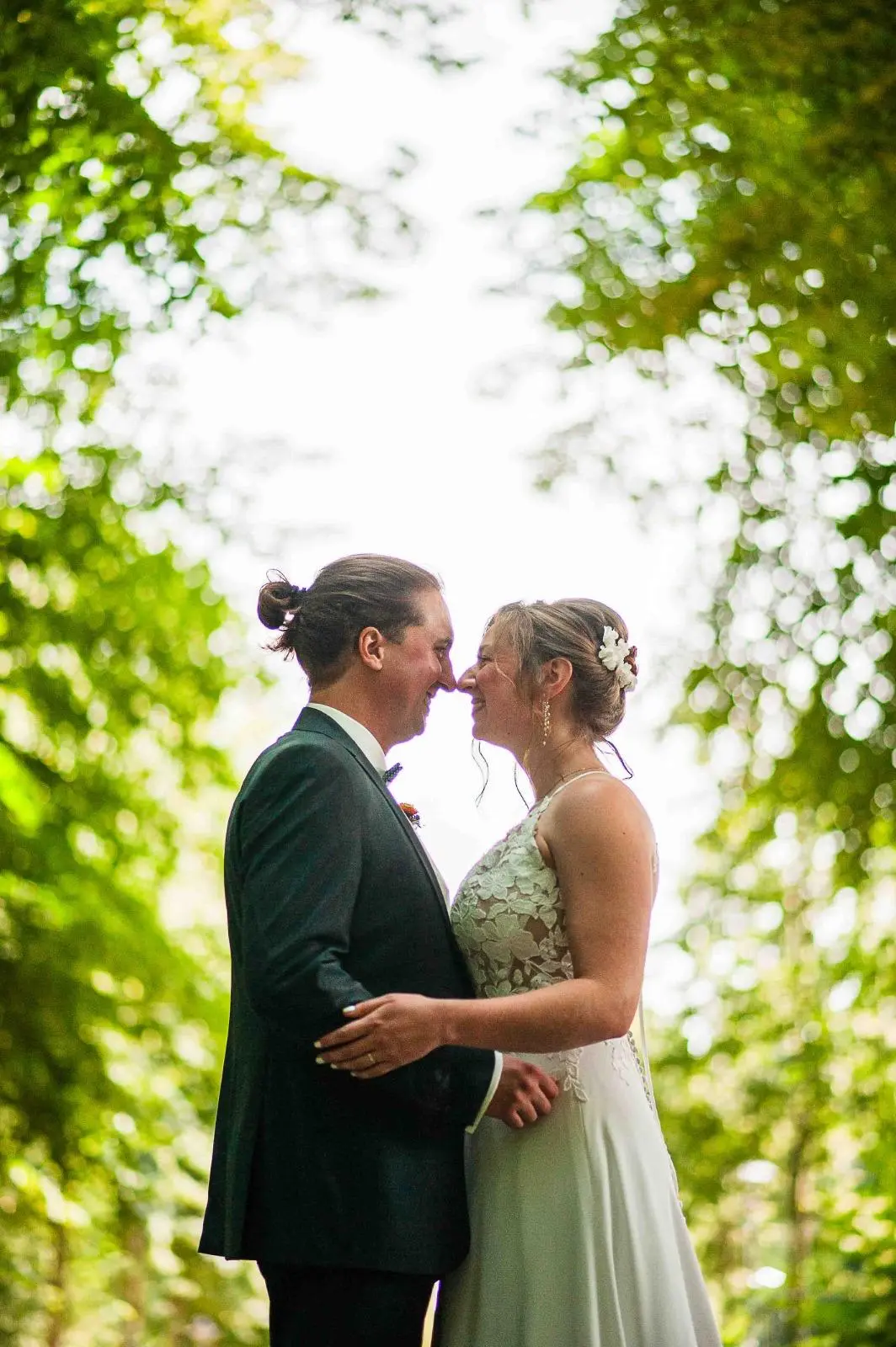 Novios abrazados bajo las hojas de un árbol