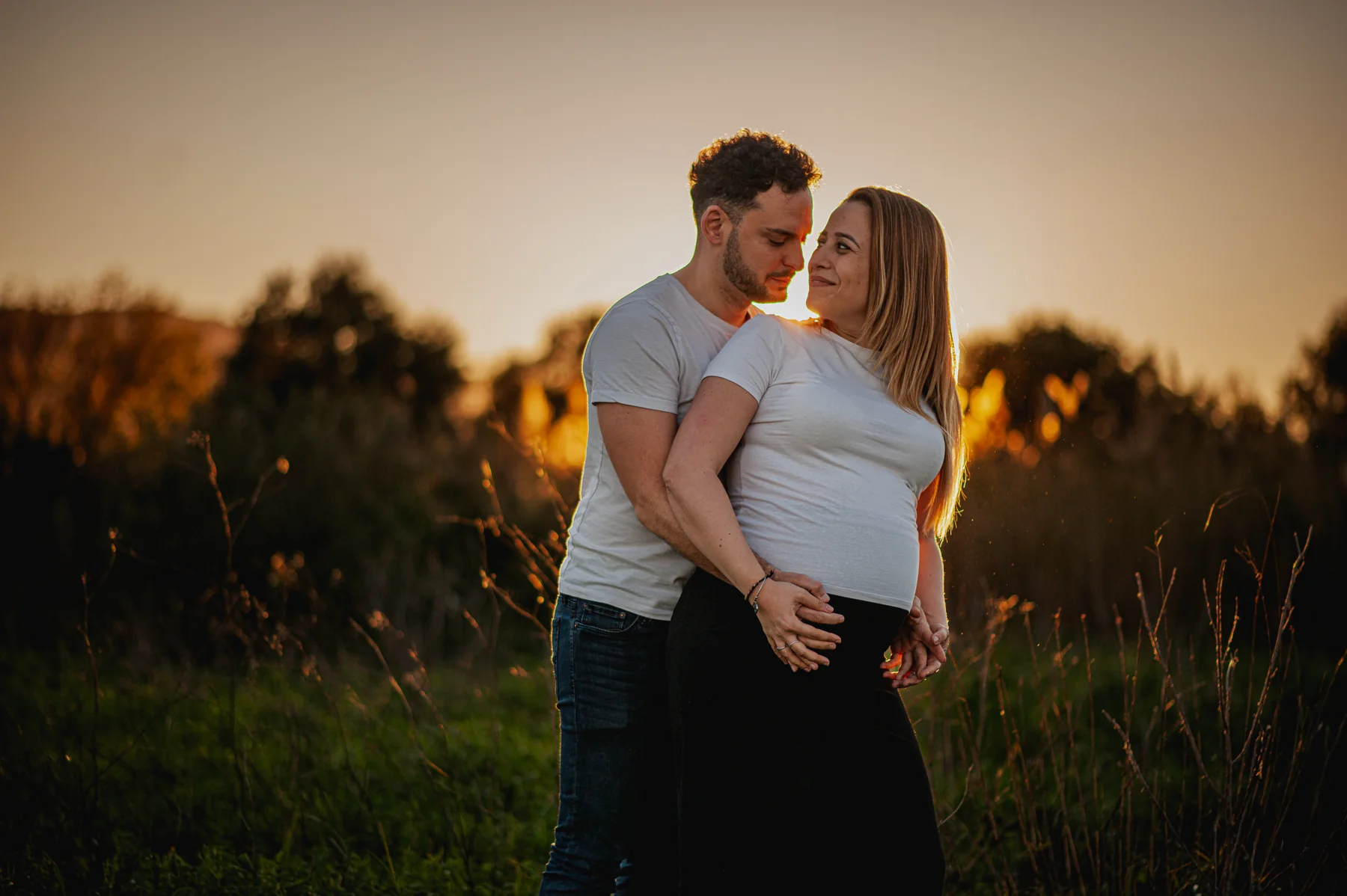 Pareja embarazada frente al cielo del atardecer
