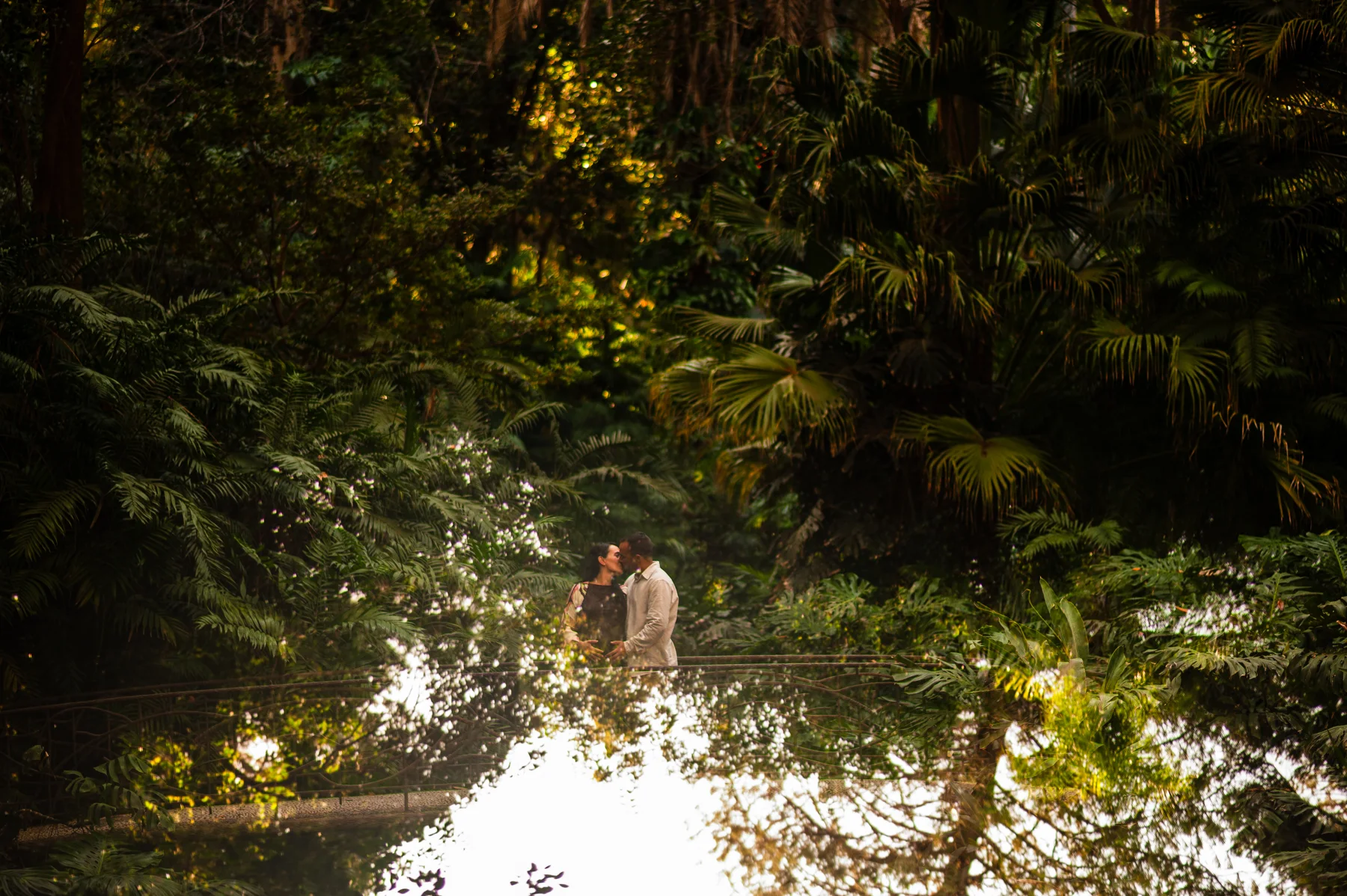 Pareja embarazada reflejada en el agua de un jardín