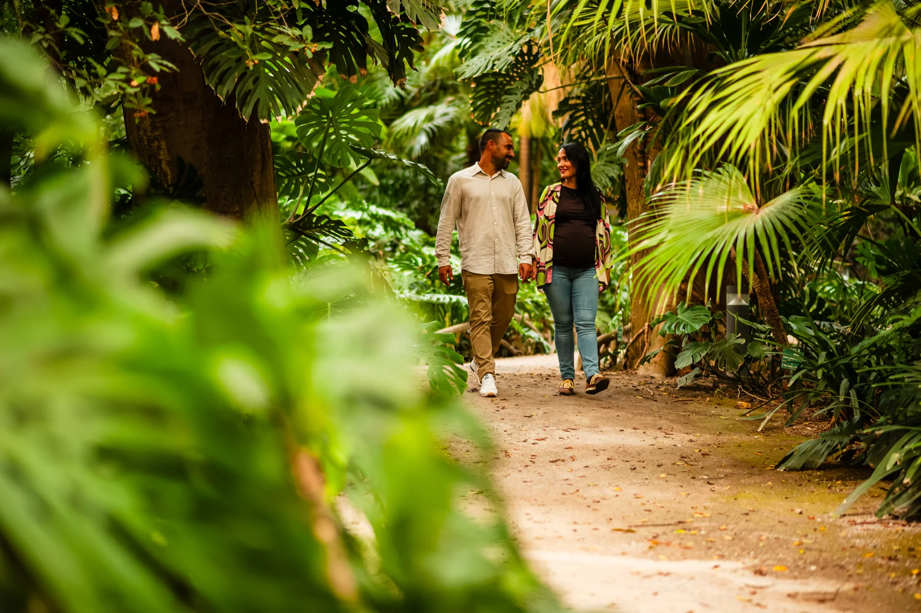Pareja caminando por un sendero entre palmeras