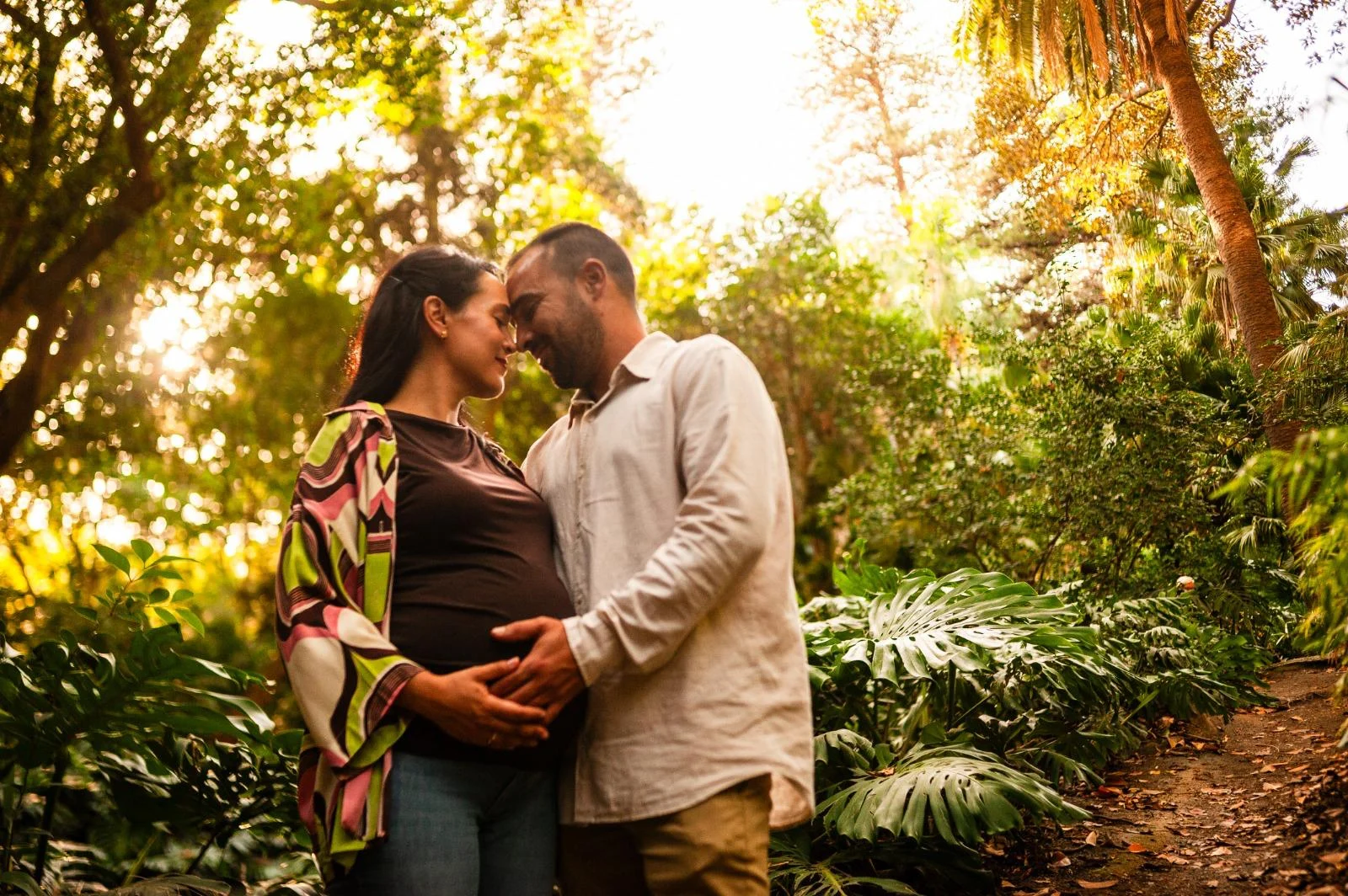 Pareja embarazada a contraluz en el jardín