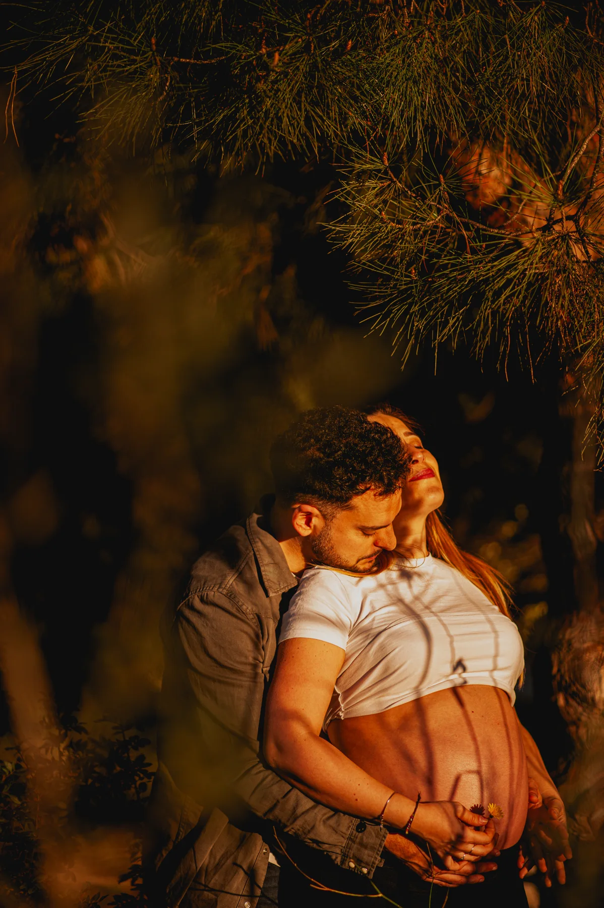 Abrazo de una pareja embarazada entre vegetación